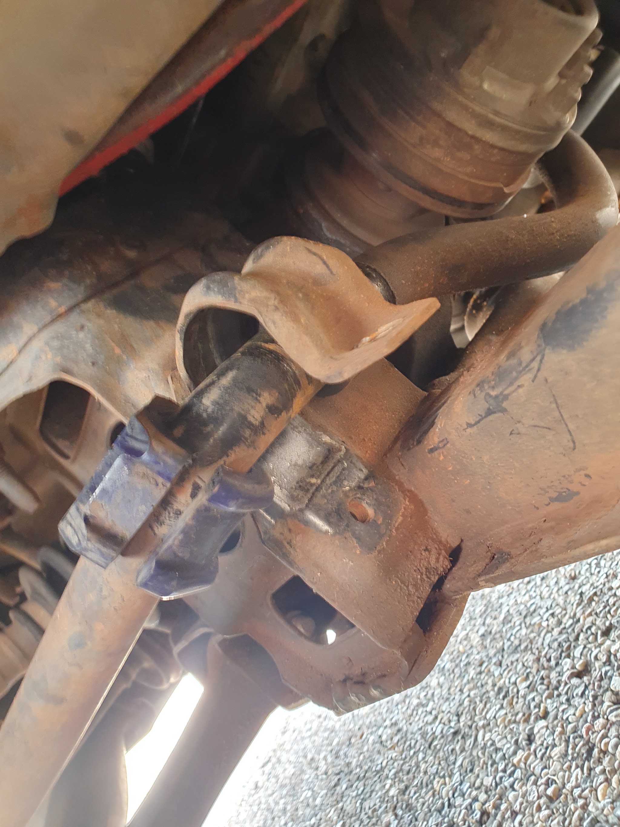 A bent torsion arm bracket photographed underneath a vehicle
